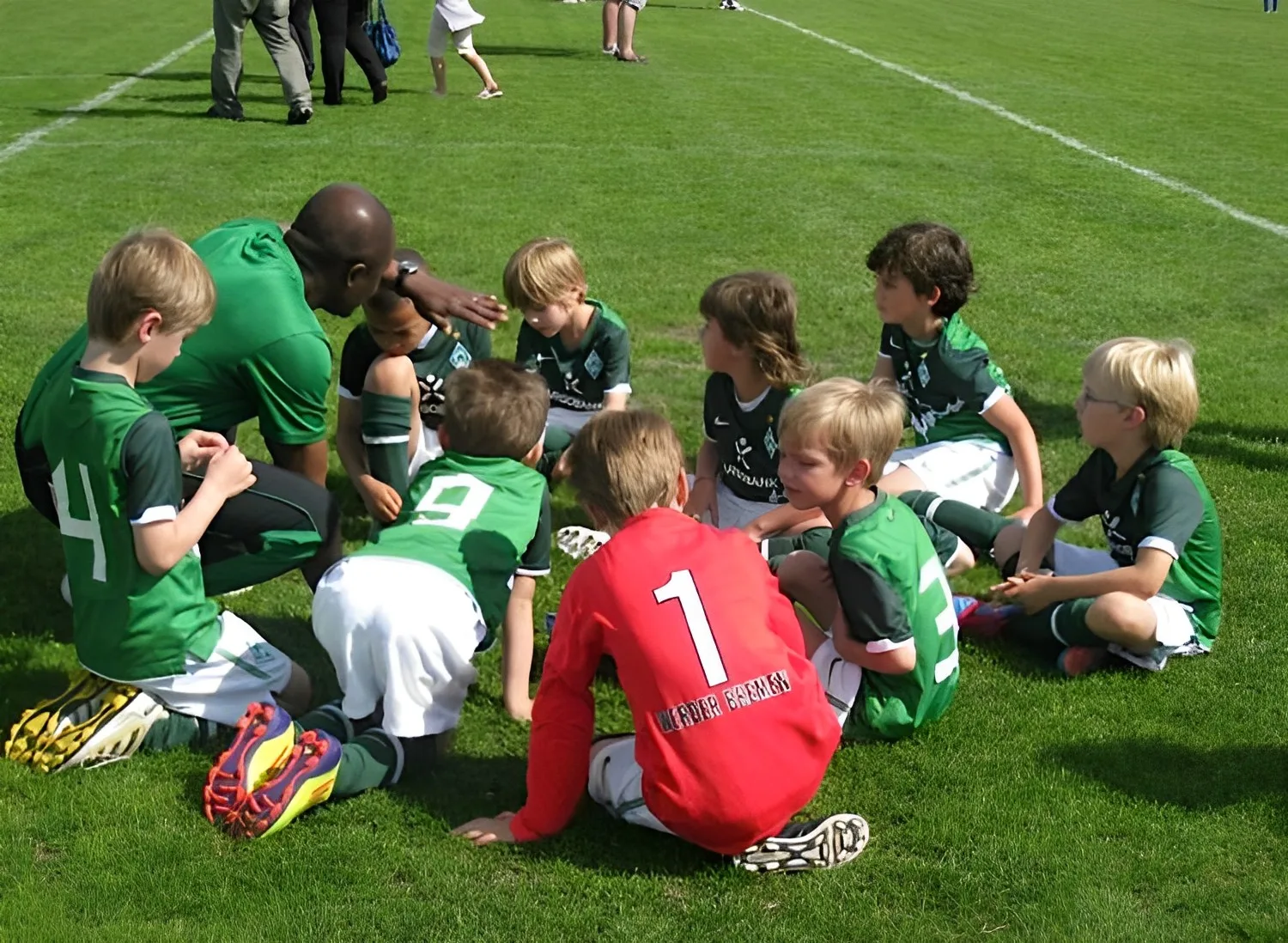 Entrenador dirigiendo una sesion de entrenamiento de futbol con niños, escena de futbol juvenil formativo