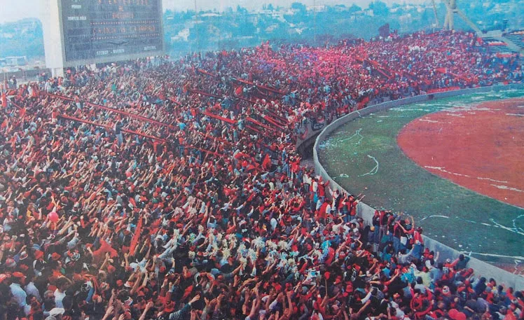 Hinchada de un club argentino alentando fielmente en la tribuna, ejemplo de pasion futbolera cotidiana de barrio