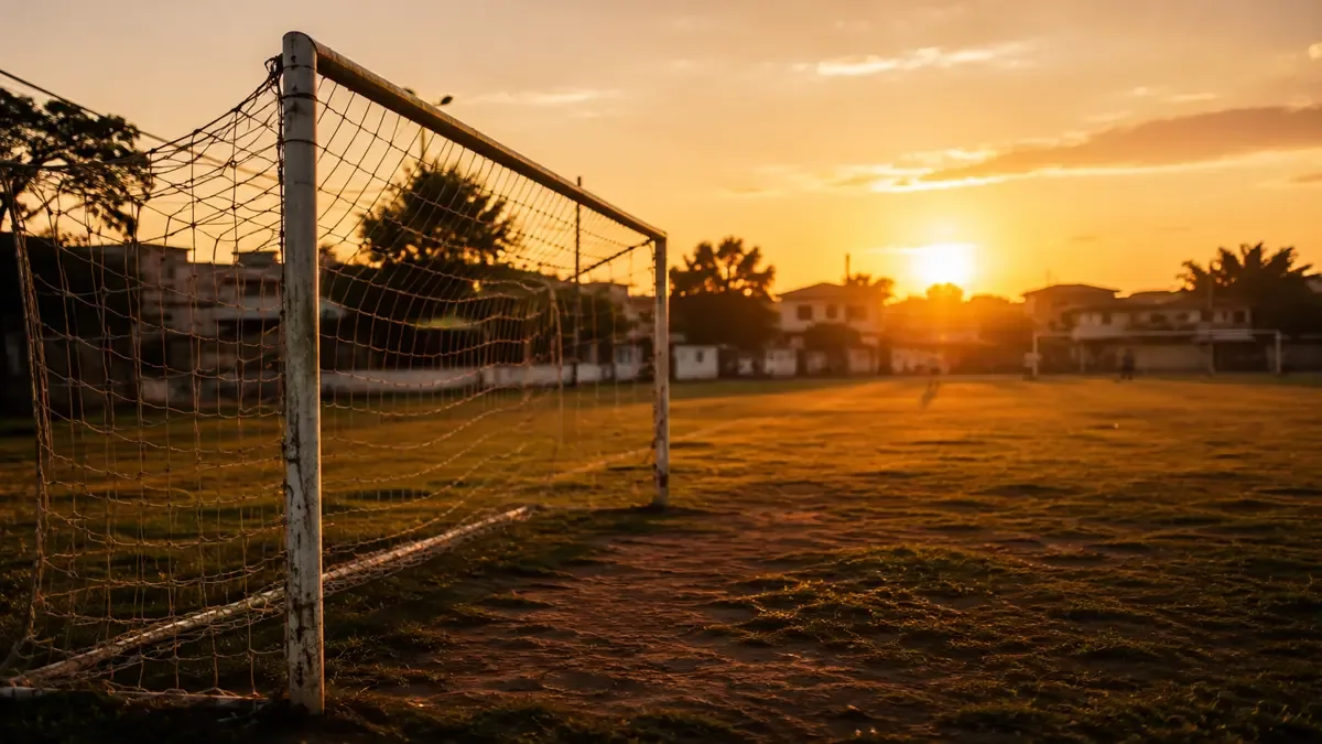 Cancha de fútbol de barrio con arco y red al atardecer